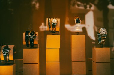 Madrid, İspanya. 1 Mayıs 2021. Erkek saatleri olan lüks bir mağazanın vitrini. Altın kahverengi ışıkta pahalı aksesuarlarla podyum yürüyüşü. Mal satmak, alışveriş, satın almak. Mağaza butik promosyonu.