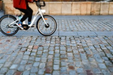 Madrid, Spain. December 1, 2022 A faceless person riding a bicycle on a cobblestone road in the old city. Eco-friendly ecological transportation to get around a town. Rent service bike company.