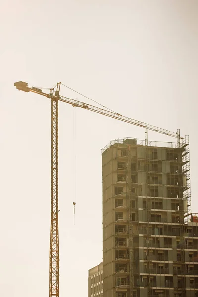 Construction mobile crane against blue sky, apartment building corner under construction. Investment in real estate. Development cities, megacities. Housing business concept. Hosting cranes high-rise.