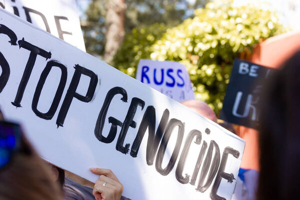 Madrid, Spain May 1, 2022 People at peace rally in support of Ukraine in war with russia. Poster with the text words 'Stop Genocide'. No war concept. Stop russian president putin. 