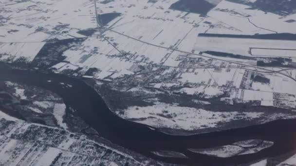 雪に覆われた土地の風景航空写真 上からの地上の眺め 寒い冬の日に飛行機で旅行する 海外での飛行 遠くへの旅行 湾曲した川や雪に覆われたフィールド 牧草地 — ストック動画