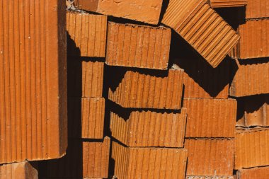 Red bricks packed in stack. Lots of new orange build bricks wall background and texture. Real estate construction, renovations. Ceramic blocks pattern. Masonry brick, brick laying. Rectangle pattern.