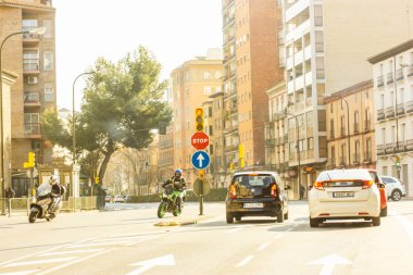 Zaragoza, Spain. February 16, 2023 Traffic on a city road on a sunny day. Infrastructure, route, jams in a big town. Urban scene, megapolis living. Transportations. Cars and motorbikes. Road signs.