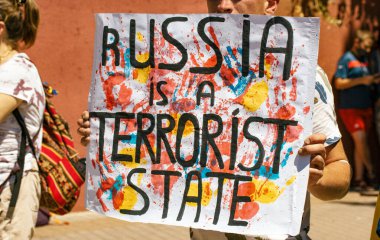 Madrid, İspanya 1 Temmuz 2022 Ukrayna 'ya destek için düzenlenen bir mitingde Rusya ile Ukrayna' ya karşı savaş ilan edildi. Rusya 'nın bir terörist devleti olduğu yazılı bir pankart taşıyan bir adam Putin' i durdurun.