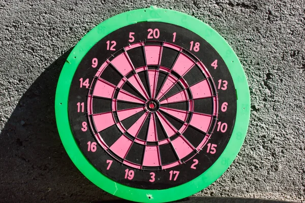 ピンクの緑のダーツは再び灰色のコンクリート壁 丸みを帯びた 赤い目のダートボードセンターリング 目的の概念 集中のための抽象円 ゲームをしろ 球状のグランジ状 — ストック写真