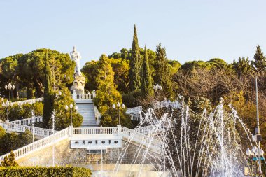 Zaragoza, İspanya. 16 Şubat 2023 Great City Park Grande Jose Antonio Labordeta Botanik Bahçesi 'nde güneşli bir günde heykeller, fıskiyeler, ağaçlar, çalılar. Dikey arkaplanda beyaz bir taş merdiven.