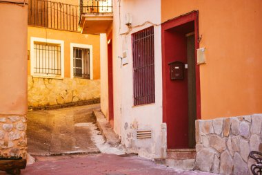 Puebla de valles, Guadalajara, İspanya. 7 Mart 2023 Tipik sarı turuncu bina cepheleri eski bir Avrupa caddesinde. Eski kırsal mimari. Apartman evleri olan eski bir sokak..