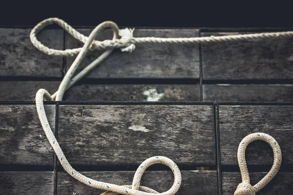 White ropes on grey vintage wooden background, deck of a ship. Nautical themed abstract background and texture top view. Ship hemp rope on a board flatly with copy space. Sea ocean knot. Retro voyage