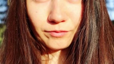Güzel, esmer bir kadının portresi. Beyaz Ukraynalı kız yüz ifadesi. Bir kadın kameraya bakıyor ve güneşli bir günde güneş ışığından eliyle yüzünü kapatıyor. Dışarıda gülümseyen tatlı bir kadın.