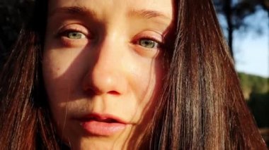 Güzel, esmer bir kadının portresi. Yüzünde sakin bir ifade olan beyaz Ukraynalı kız. Sıcak ve güneşli bir günde kameraya bakıp güneşin tadını çıkaran bir kadın. Yaz parkında gülümseyen tatlı kadın..