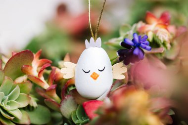 Güneşli bir günde bahar bahçesinde çiçek açan çiçeklerin arasında tatlı bir tavuk şeklinde paskalya yumurtası. Paskalya duvar kâğıdı. Çok güzel bir tebrik kartı. Bahar dini bayramı için dekor.. 