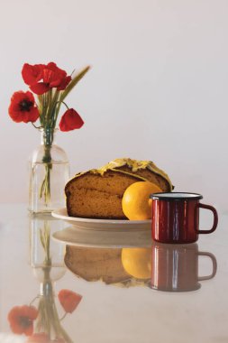 Kırsal yaşam, cam vazoda kırmızı haşhaş ve mutfak masasında biscocho Bizcocho limonlu kek. Evde hazırlanmış tatlı. Kırmızı bir fincan kahve ya da çay. Bisküvi pastaları, kekler.. 