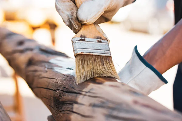 顔のない大工さんは 表面を接着剤で処理して虫から守ることで木材を使っています 筆を持つ大工の仕事 木で作られた製品 木の丸太 木材染色 — ストック写真