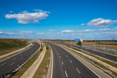 Madrid İspanya 15 Nisan 2023 Asphalted yolu, otoyol uzak bir viraja girer, ilkbahar veya yaz günü mavi bulutlu gökyüzü ile güzel bir manzara. Arabayla seyahat, ulaşım.
