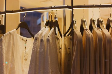 Madrid, İspanya 1 Mayıs 2022 Kadın giyim mağazası. Beyaz bluzlar vitrindeki askılara asılıyor. Güzellik, moda işi konsepti. Kadın gömleği, kazak, elbise. Giysi rafı.