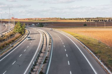 Madrid, İspanya 25 Nisan 2023 dört şeritli asfalt bir otoyol ufukta bir mesafeye gider. Güneşli bir günde seyahat etmek. İspanyol çayırlarından, gündüz çayırlarından geçeceğiz. Az trafik
