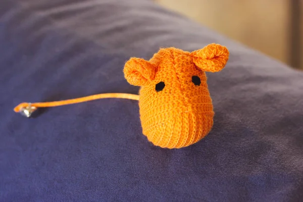 A cute handmade knitted orange toy mouse. A hobby of making toys for pets. Decorative crocheted mouse for cats. Cute soft animal. Kraft toys for children to play. Childhood concept. Domestic animal.