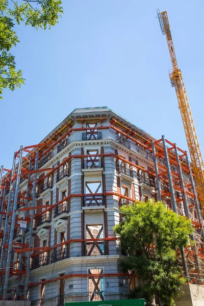 stock image Madrid, Spain. May 9, 2022. Restoration construction of an old apartment building, house facade. Renovation of vintage property. Construction site with metal scaffolding Exterior windows without glass