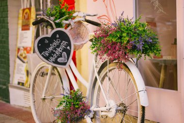 Madrid, İspanya. 1 Mayıs 2023 Beyaz antika bisiklet ve çiçek desenli sepet ilkbahar günü şehir caddesinde park halinde duruyor. Seyahat için çevre dostu bir çift tekerlekli. Sürdürülebilirlik ekoloji.