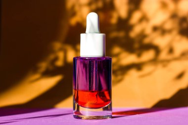 Kahverengi doğal arka planda bitki örtüsü desenli cam bir yüz serumu kavanozu. Kozmetik ve vücut bakımı. Kütikül yağı. Pipetli kozmetik şişesi. Minimalist stil günlük bakım.