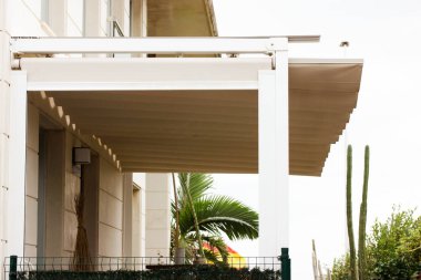 Attached pergola on a villa in Spain. A modern or classic hotel on the tropical resort. White wooden long courtyard canopy over house entrance, cottage. Front door canopies.  clipart