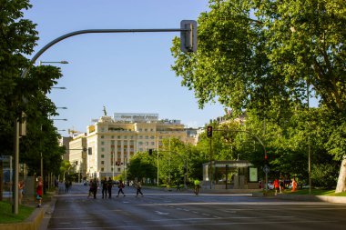 Madrid, İspanya. 1 Temmuz 2022 Şehir Caddesi. Trafik ışığı, insanlar caddeyi geçerken kırmızı ışıkta araba trafiğini yasaklıyor. Metropol yeşil ağaçlara, çalılara gömülmüş. Yeşil şehir bölgesi. 