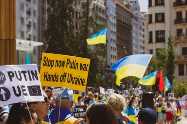 Madrid İspanya. 12022 Haziran 'ında Ukraynalıların sloganlarını destekleyen posterli protestocular artık savaş ilan ediyorlar. Ukrayna 'dan uzak dur. Artık savaş ve Rus saldırıları yok. Ukrayna 'da kal. Ukrayna bayrağı