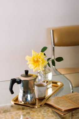 Madrid, İspanya. 1 Mayıs 2023 Masanın üzerinde açık eski bir kağıt var. Altın tepside çay ya da kahve, sarı gül çiçekli vazo. Rahat bir iç mekan için ev dekorasyonu. Edebiyat okuyorum, rahatla..