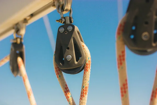 stock image Ship block with ropes. Steel sling and rope clamp connected by screw bolt. Device for adjusting the tension or length of ropes on the deck of a ship, yacht. Boat parts. Roller blocks against blue sky.