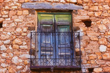 Çok eski yeşil mavi balkon. Kırık ahşap balkon kapılı, metal parmaklıklı antik bir kırmızı tuğla ev. Dışarıdaki terk edilmiş eski bina. Seyahat fotoğrafçılığı. Mimarinin klasik detayları.