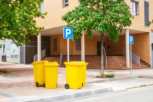 スペインのマドリード 2023年6月5日住宅街のマンション近くの街中に黄色いプラスチックごみ缶が立っている 都会の風景 生態系 青の障害者用駐車標識 — ストック写真