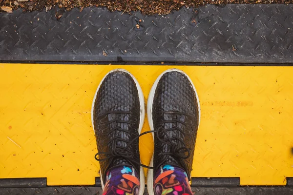 ホイールバンプラバーブラックイエローとブラックスニーカーの女性の足と明るいスタイリッシュな靴下トップビュー 秋の日に旅行 寒い季節の靴 履物の概念 女性観光客が世界を発見 — ストック写真