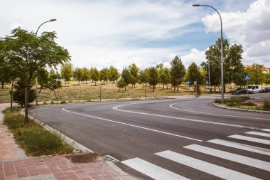 Asfalt bir yol köşeden keskin bir dönüş yapar. Şehir ortamında yaya geçidinde beyaz işaretler. Büyük şehir altyapısı. Yaya geçidi, zebra beyazı işaretler. Yollar dönüyor.