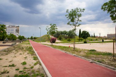 Bir bahar ya da yaz gününde şehir parkında kırmızı düz bisiklet yolu. Açık hava sporları için altyapı, doğa. Caddedeki bisiklet yolu. Kasvetli bir günde insanların olmadığı şehir manzarası. Bisikletçi yolu.