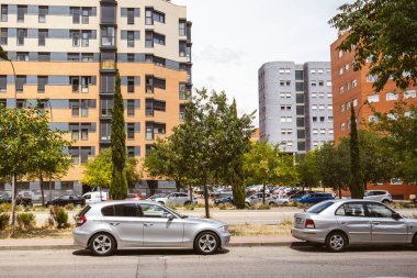 Madrid, İspanya. 1 Mayıs 2023 Güneşli yaz gününde bir şehir caddesi. Arabalar yol kenarına park edilmiş. Modern sessiz yerleşim yerlerinde çok katlı binalar. Şehir manzarası. Farklı mimari.