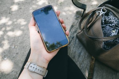 Elinde akıllı telefon kullanan bir kadın vardı. Şehir parkında oturan, dinlenen, mesajlaşan, sosyal medyayı kullanan bir kız. Modern insanların yaşam tarzı. Güneşli bir günde dışarıda iş kadını. Cep telefonu kullan.. 