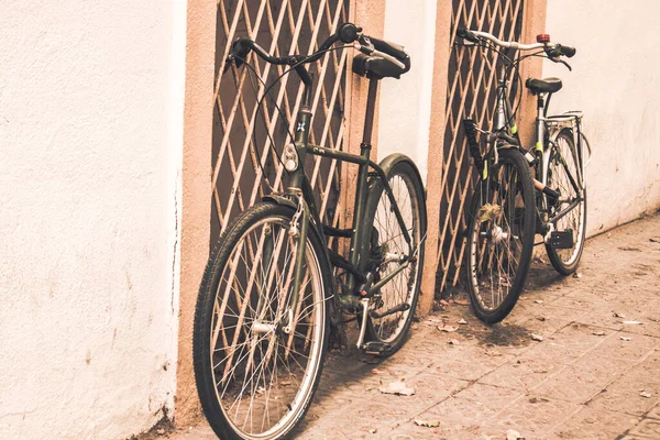 マドリード スペイン 2023年8月1日 2台の古い黒い自転車が市街地の壁の近くに駐車した 暖かい茶色のフィルターが付いている懐かしい写真 エコロジカルな都市交通 暖かい晴れた日に自転車に乗る — ストック写真