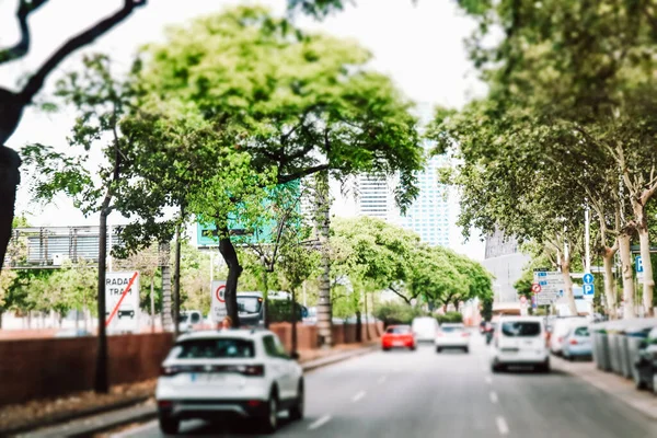 Green city landscape. Car traffic on city road tilt shift. Urban environment, zone with green trees. Modern fast pace of life. People in automobiles rushing to work. Alley, roadway in summer day.
