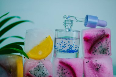 Kozmetik serumu cam şişede pipetle buz küplerinde taze pitaya ya da ejderha meyvesi ve limonlu narenciye. Yüz bakımı için doğal kozmetik ürünleri. Yüz, vücut ve saç için yenileme yağı. 