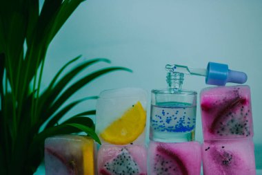 Kozmetik serumu cam şişede pipetle buz küplerinde taze pitaya ya da ejderha meyvesi ve limonlu narenciye. Yüz bakımı için doğal kozmetik ürünleri. Yüz, vücut ve saç için yenileme yağı. 