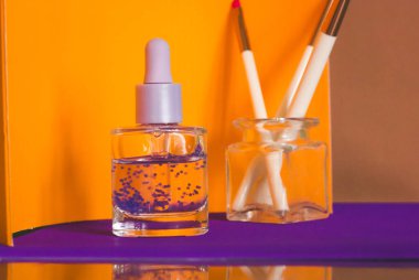 Hyaluronik asit, turuncu arka planda pipeti olan cam bir şişede. Yüz bakımı ya da tırnak içi yağı makro fotoğrafı. Hidro güçlendirici serum yaşlanan cilt için aktif nemlendirici sağlar. Kadın kozmetik masası