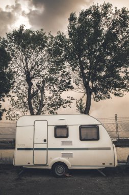 Park kamp alanındaki tatil karavanı. Konut tipi bir araç kasvetli bir sonbahar gününde caddede park halinde. Beyaz yarış arabası. Mobil ev otomobili. Klasik karavan monokrom fotoğrafı..