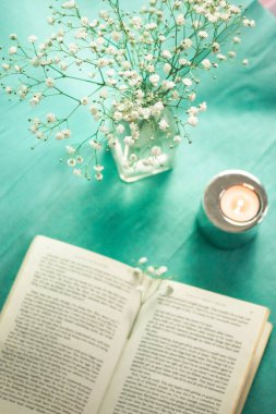 Madrid, İspanya 1 Mayıs 2023 Yeşil masa manzaralı açık bir ciltli kağıt kapak. Küçük narin beyaz çiçekli vazo, bahar için ev dekorasyonu. Sakinleşmek, okumak, çalışmak. Çalışma alanı