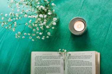 Madrid, İspanya 1 Mayıs 2023 Yeşil masa manzaralı açık bir ciltli kağıt kapak. Küçük narin beyaz çiçekli vazo, bahar için ev dekorasyonu. Sakinleşmek, okumak, çalışmak. Çalışma alanı