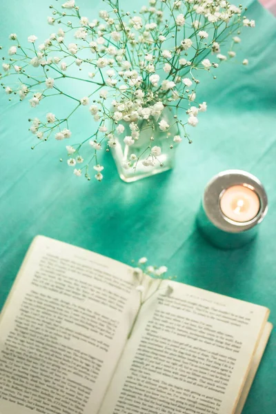 Madrid, İspanya 1 Mayıs 2023 Yeşil masa manzaralı açık bir ciltli kağıt kapak. Küçük narin beyaz çiçekli vazo, bahar için ev dekorasyonu. Sakinleşmek, okumak, çalışmak. Çalışma alanı