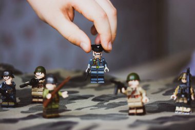 Kyiv, Ukrayna. 9 Mart 2022. Çocuğun elindeki memurun heykeli. Bir çocuk İkinci Dünya Savaşı 'nın LEGO askerlerini oynuyor. Kamuflaj üniformalı oyuncak askerler, makineli tüfek. Silahlı kuvvetlerin savaş askeri oluşumları