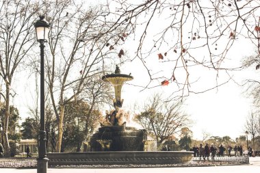 Madrid, İspanya. 1 Mayıs 2021 Galapagos Çeşmesi İspanyol başkentinin merkezinde, Buen Retiro Parkında. Şehir meydanındaki çeşme. Çıplak ağaçlarla dolu sonbahar doğası. İnsanlar hafta sonları sokakta yürürler.
