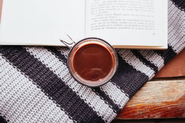 Madrid, İspanya Ekim 12023 örülmüş mavi eşarp ya da süveter arkaplan üzerine açık bir kağıt kitap. Kırsal bir yaşam tarzının rahatlığı. Yavaş yaşam. İçeride edebiyat okuyorum. Bir kitap ve bir kupa üst görünümü.