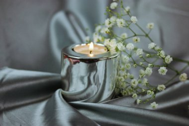 Beyaz, taze çiçek açan kaplıca hayatı, ipek gri arka planda yanan metalik mum. Düğün aksesuarları, çiçek aranjmanı, buketten filizlenen çiçek. Evde dinleniyorum..