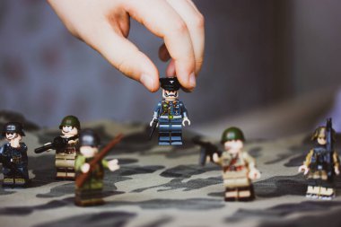 Kyiv, Ukrayna. 9 Mart 2022. Çocuğun elindeki memurun heykeli. Bir çocuk İkinci Dünya Savaşı 'nın LEGO askerlerini oynuyor. Kamuflaj üniformalı oyuncak askerler, makineli tüfek. Silahlı kuvvetlerin savaş askeri oluşumları